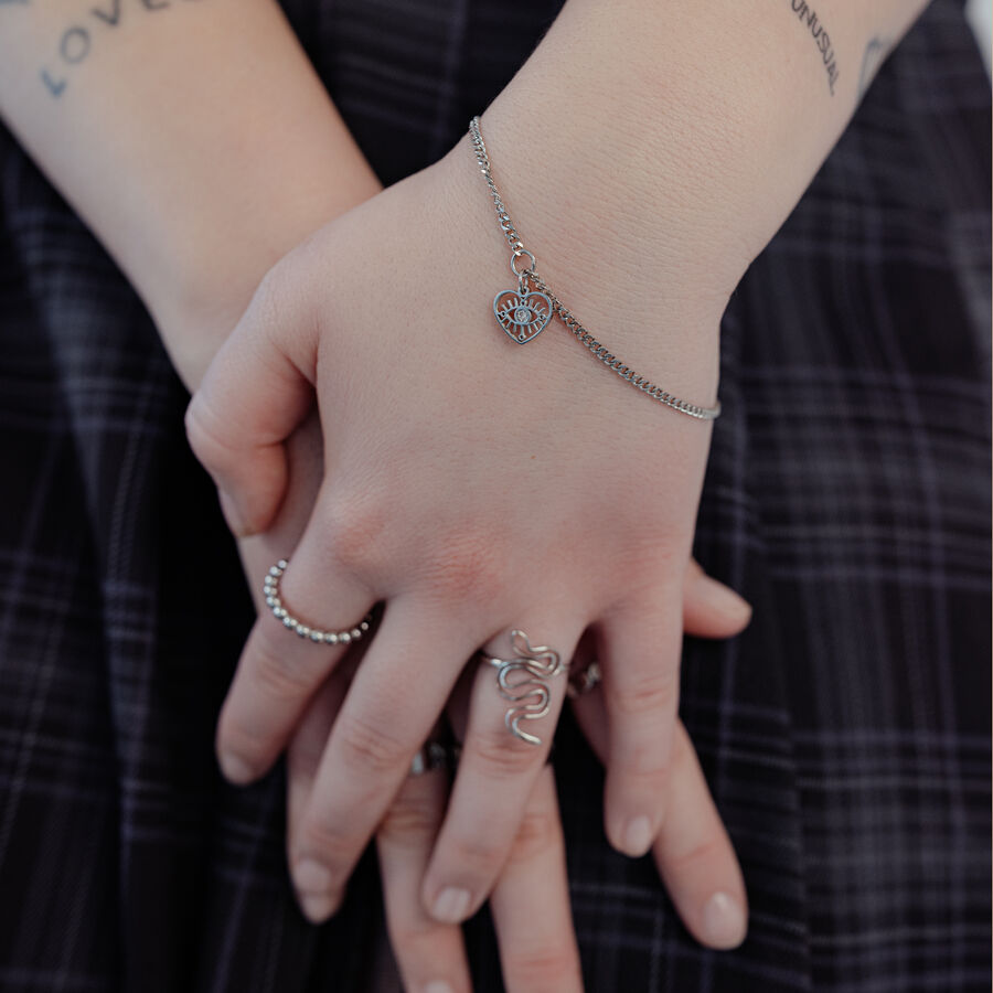 Bracciale d'argento con ciondolo a cuore al polso, indossato da una persona.