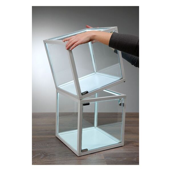Due cubi vetrina di vetro bianchi con strisce LED su tavolo di legno, una mano solleva il cubo superiore