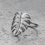 Silberner Monstera Blatt Ring aus Chirurgenstahl auf grauem Hintergrund