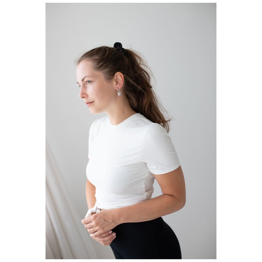 Donna con t-shirt bianca e eleganti orecchini in argento su sfondo neutro