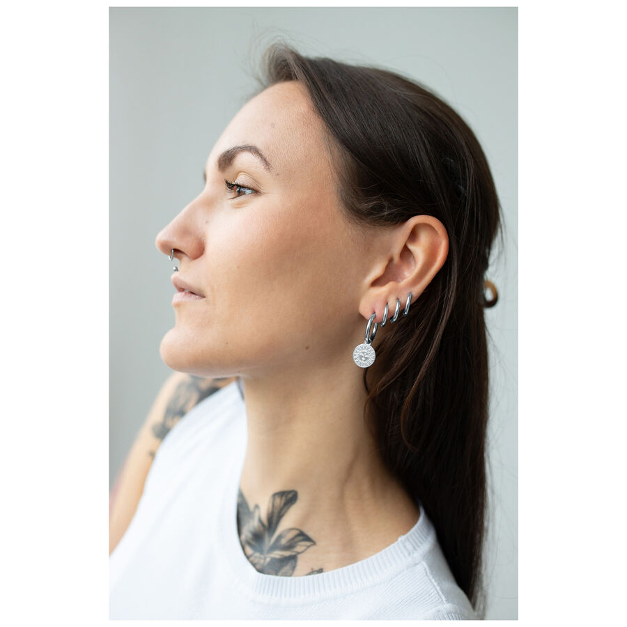 Mujer con cabello largo lleva aros de plata con diseño de luna