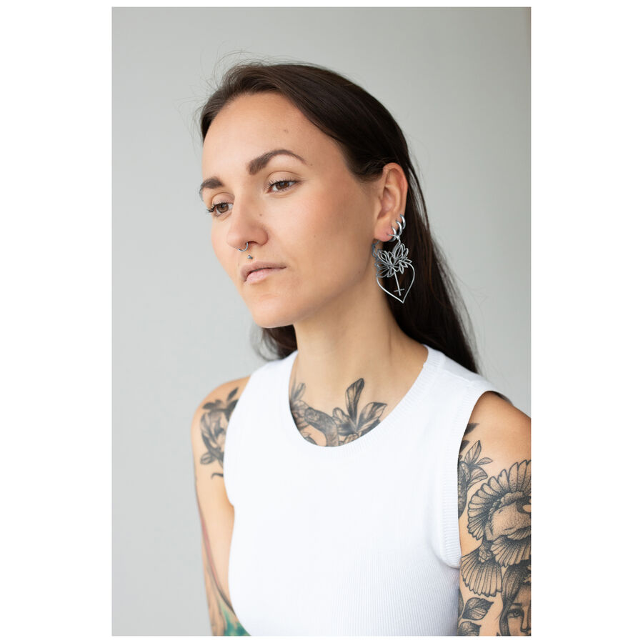 Mujer con cabello largo lleva aros Dahlia de plata sobre fondo gris