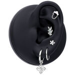 Soporte de modelo de oreja negro con varias joyas, incluyendo un Hinged Ring de oro blanco con colgante de flor.