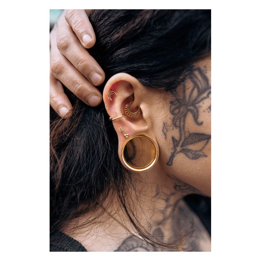 Persona con Barbell Triplet dorado y otros piercings en la oreja