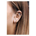 Piercing Triangle Barbell in oro all'orecchio di una persona con altri piercing e tatuaggio sull'orecchio