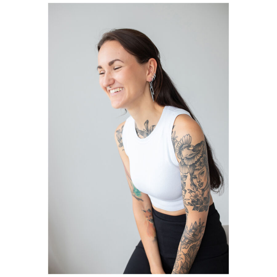 Mujer con cabello largo y tatuajes lleva aretes Thunderbolt Hoops, top blanco