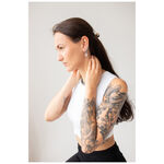 Donna con capelli lunghi e tatuaggi indossa orecchini Little Eye Hoops