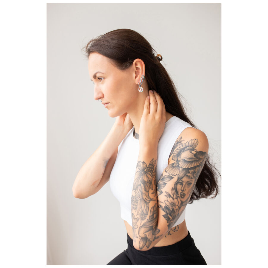 Mujer con cabello largo y tatuajes lleva pendientes Little Eye Hoops