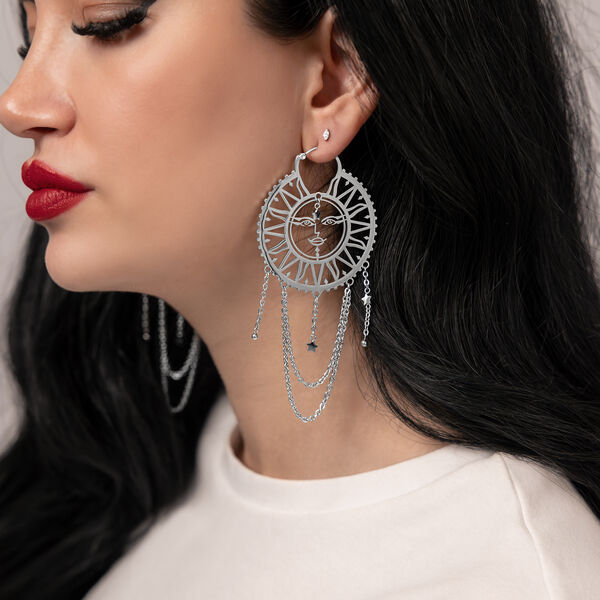 Pendientes plateados con diseño de sol y luna en mujer de cabello oscuro