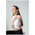 Persona sorridente con capelli lunghi e Selflove Club Hoops in una stanza luminosa
