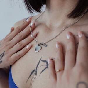 Gravierbare Basic Kette aus Chirurgenstahl Silberne Kette mit gravierbarem Herzanhänger auf Haut mit Tattoos